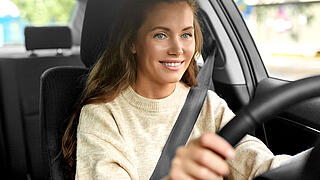 safety and people concept - happy smiling young woman or female driver driving car in city