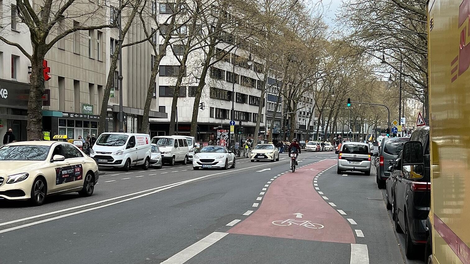 Radverkehrsführung in Knotenpunkten mit mehreren Kfz-Fahrstreifen: Leitung des Radverkehr auf eigene, unterbrochen markierte und Rot eingefärbte Fahrstreifen zwischen den Kfz-Fahrstreifen; rechtsabbiegende Radfahrende verbleiben auf dem hier beginnenden Rechtsabbiegestreifen