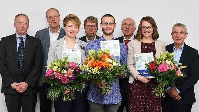 Die DVR-Förderpreisgewinner 2019 mit Blumensträußen und Urkunden in den Händen, welche gemeinsam mit den Juroren vor weißer Wand stehen.