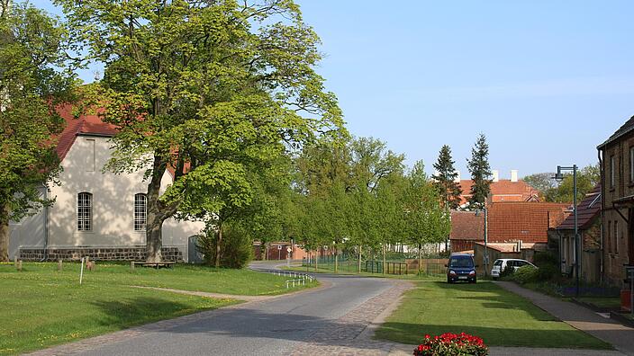 Bild 1: Die Dorfstraße nach dem Umbau: dem Dorfgrundriss und Verkehrsaufkommen angepasste Linienführung und Dimensionierung der Geh- und Fahrflächen, durch Versickerungsmulden abgesetzt