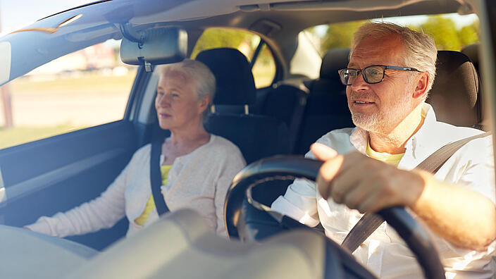 Älteres Ehepaar im Auto, er fährt.