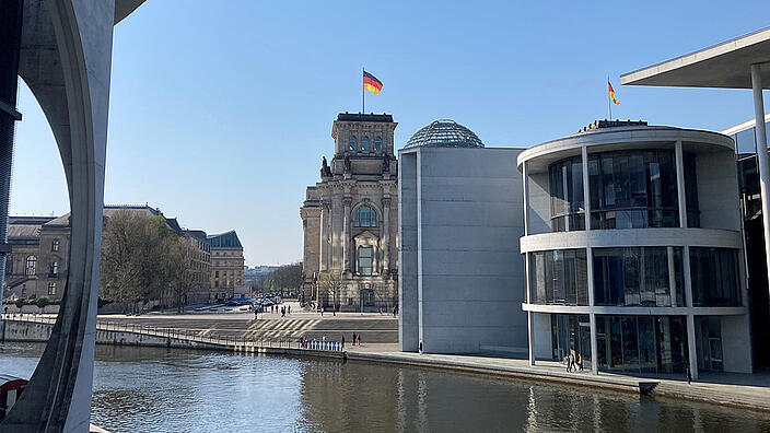 Blick über die Spree auf einen Teil des Reichstagsgebäudes, rechts und links im Bild sind zwei weitere Gebäude des Bundestags.