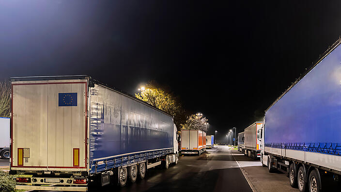 Lkw auf einem Stellplatz an einer Autobahnraststätte im Dunkeln.