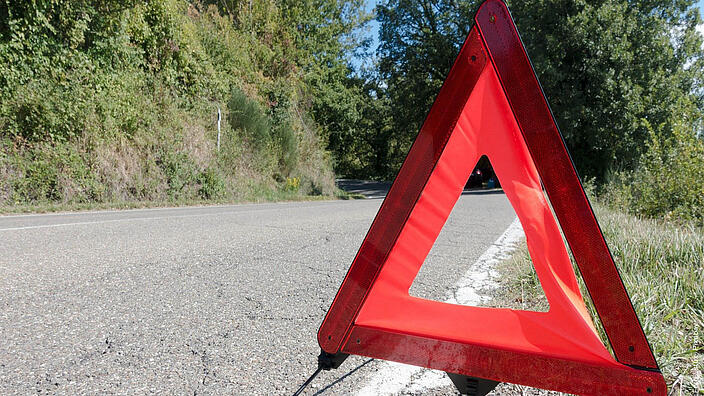 Ein Warndreieck auf einer kaputten Landstraße