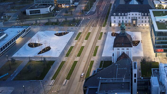 Der Emanuel-Merck-Platz nach dem Umbau: gestalterische Integration des Verkehrsraums der Frankfurter Straße in die beiderseits liegenden Platzbereiche mit Auflösung der Kfz-Fahrbahn in zwei Richtungsfahrbahnen und Realisierung von linear wirksamen Elementen zur Sicherung der Überquerbarkeit und des Zugangs zur Straßenbahnhaltestelle