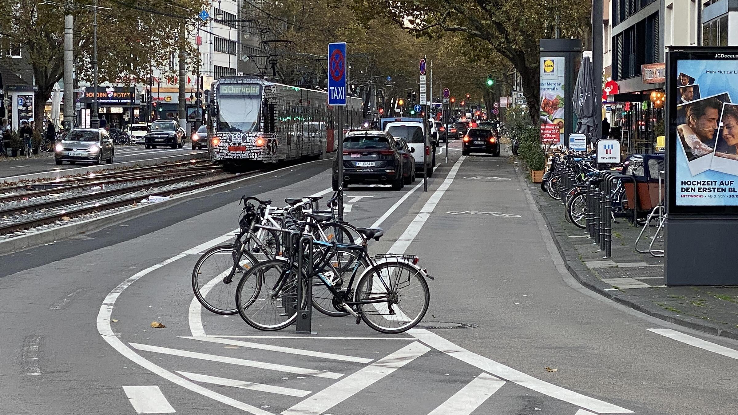 Sonderlösung im Querschnitt: ausgehend von der Knotenpunktausfahrt sind Taxistände, Fahrradparken und Liefern/Laden in Fahrbahnmitte angeordnet, vormalige Längsparkstände am Fahrbahnrand wurden mit Bügeln zum Abstellen von Fahrrädern ausgestattet oder für außengastronomische Nutzungen freigegeben