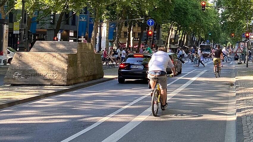 Quer verlaufende Nebenachse des Radverkehrs: eigene Radverkehrssignalisierung mit kurzen, auf der Außenseite neben den Radfahrstreifen angeordneten Aufstellflächen für den vom Habsburger Ring auf die Achse abbiegenden Radverkehr; an dieser Stelle sind bei Grün Querende zu Fuß und mit dem Rad aus der Perspektive des Hohenzollernrings zu erkennen