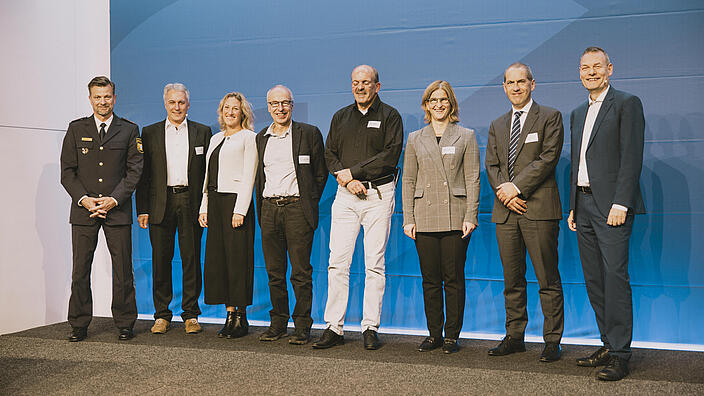 Die Referentinnen und Referenten der Juristischen Fachkonferenz stehen nebeneinander auf der Bühne. 