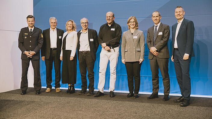 Die Referentinnen und Referenten der Juristischen Fachkonferenz stehen nebeneinander auf der Bühne. 