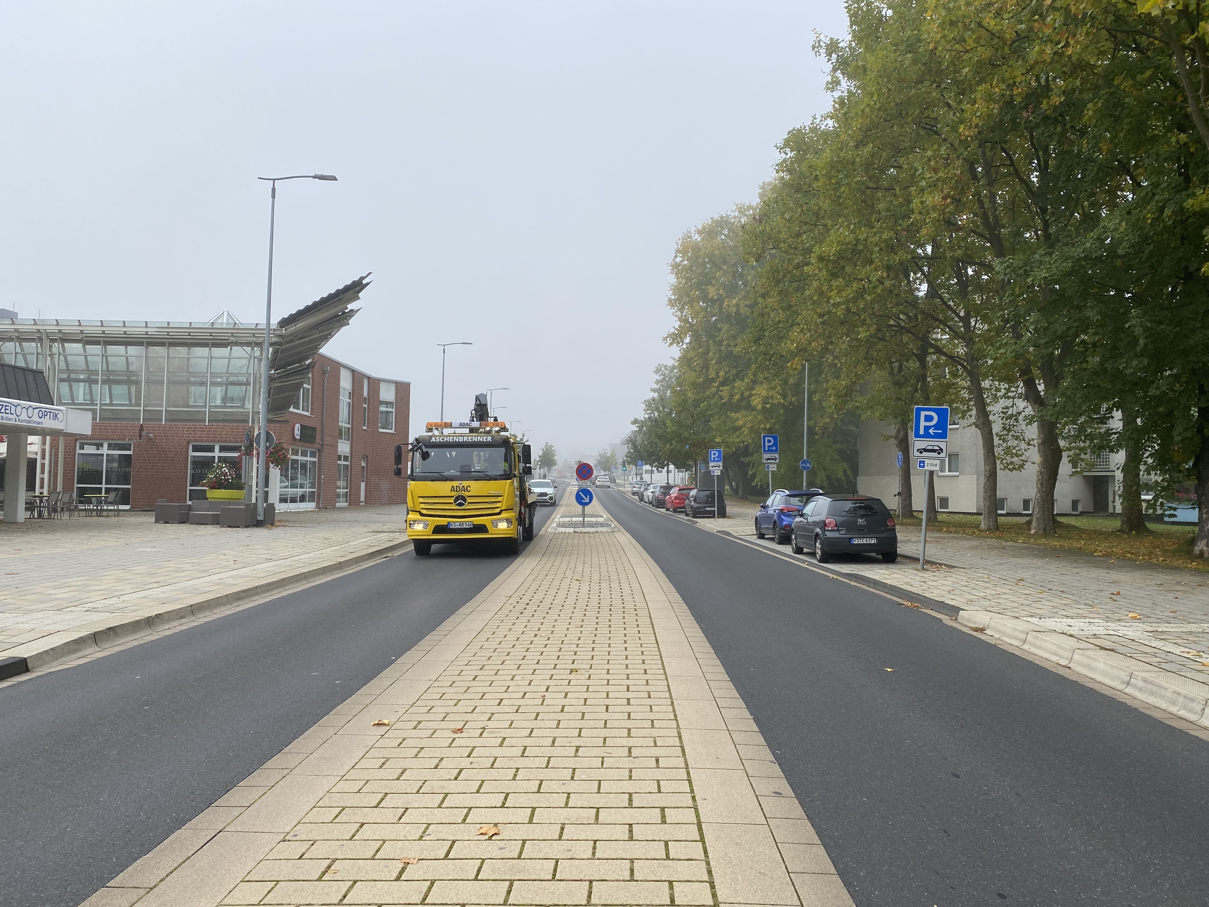 Bild 12: Realisierter Fahrbahnquerschnitt: einstreifige Richtungsfahrbahnen in 3,25 m Regelbreite, durch einen niveaugleich gepflasterten Mittelstreifen getrennt, der überfahren und von Zufußgehenden zum Überqueren der Fahrbahn in zwei Zügen genutzt werden und bei der gegebenen Breite von 2,50 m auch bauliche Fahrbahnteiler und Mittelinseln als gesicherte Querungsstellen – hinten im Bild – gut aufnehmen kann