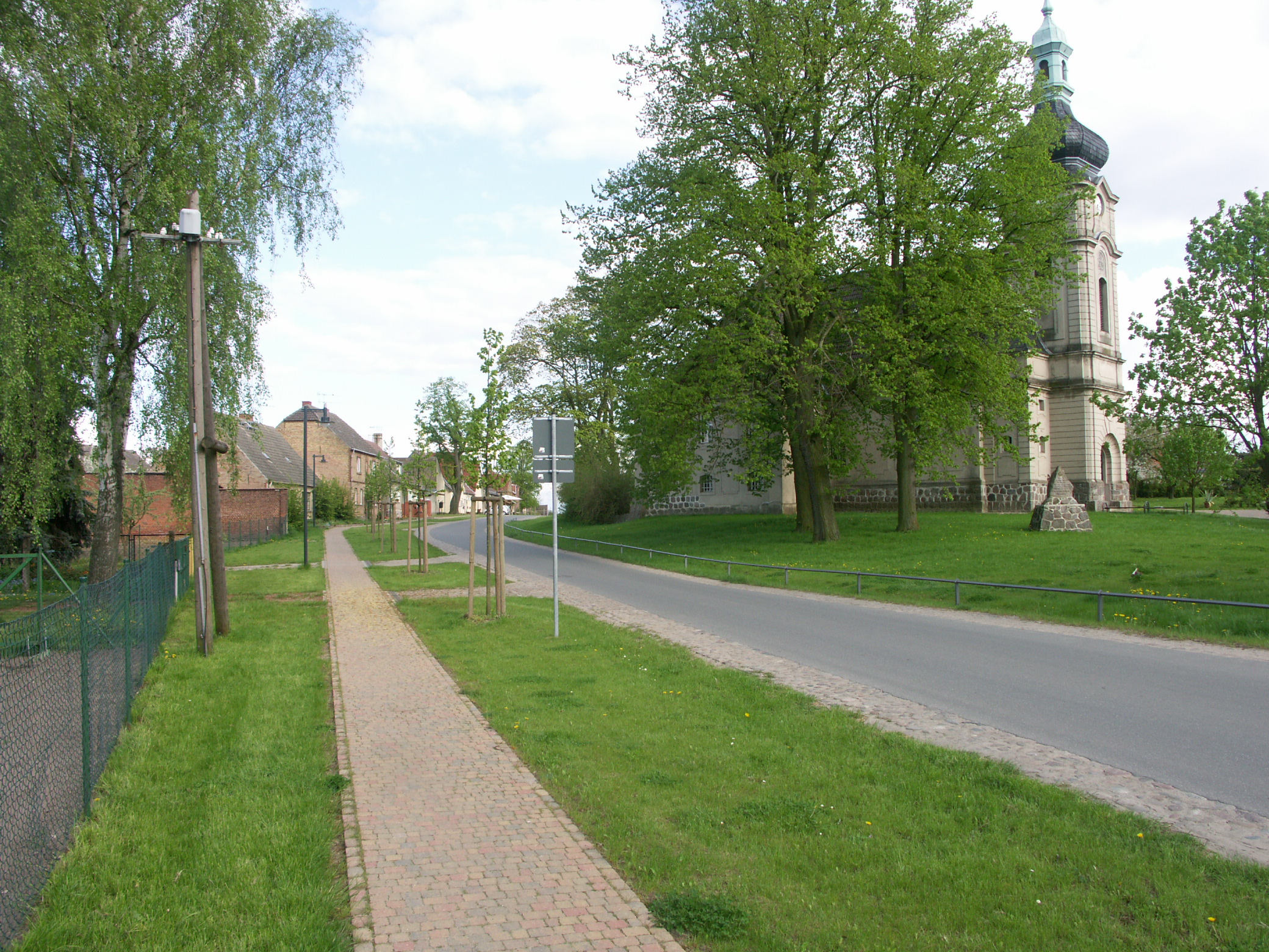 Bild 17: Dorfstraße am Anger: dezente Anpassung der Straßenraumgestaltung an die dominante städtebaulich-räumliche Situation von Angerfläche, Dorfkirche und angrenzender Bebauung